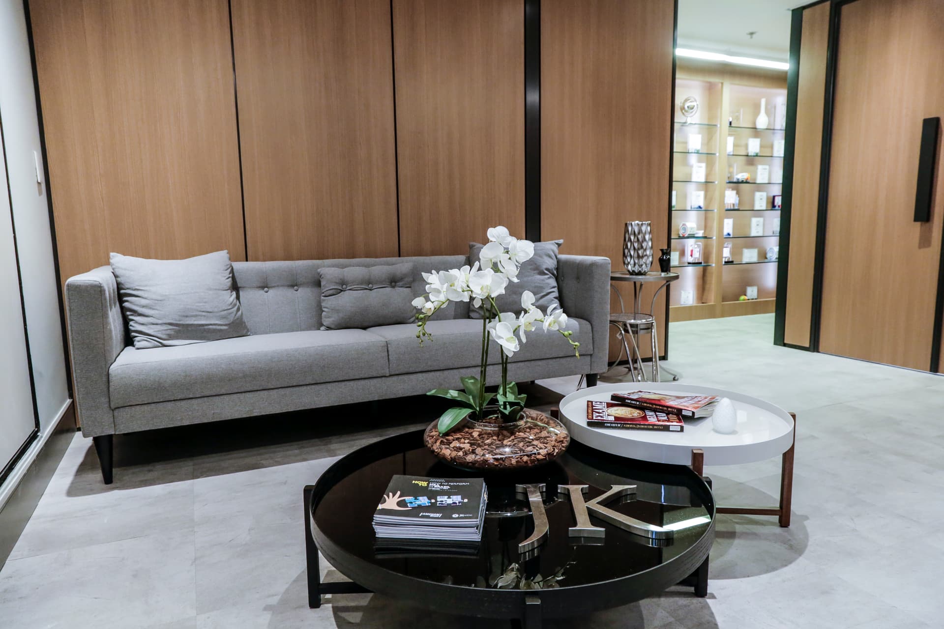 Reception area of JK Capital's office in São Paulo, with a gray sofa and light wood paneling